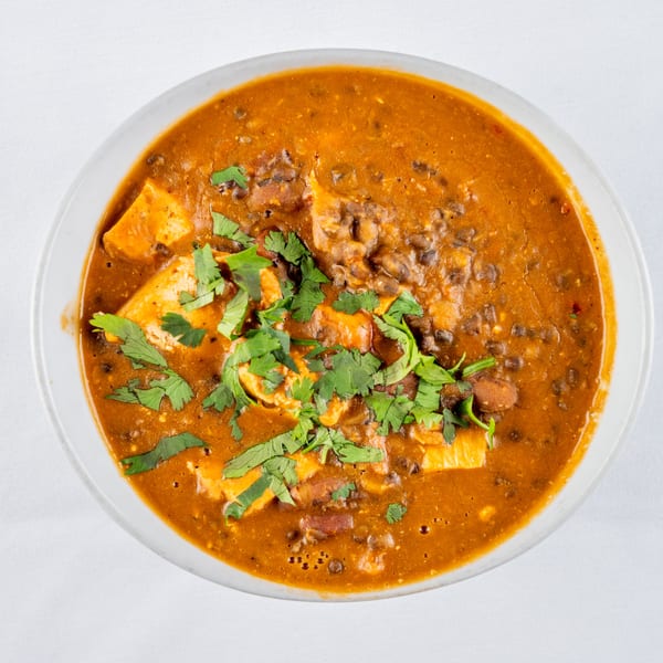 Overhead view of a bowl of Indian curry with paneer and cilantro garnish.